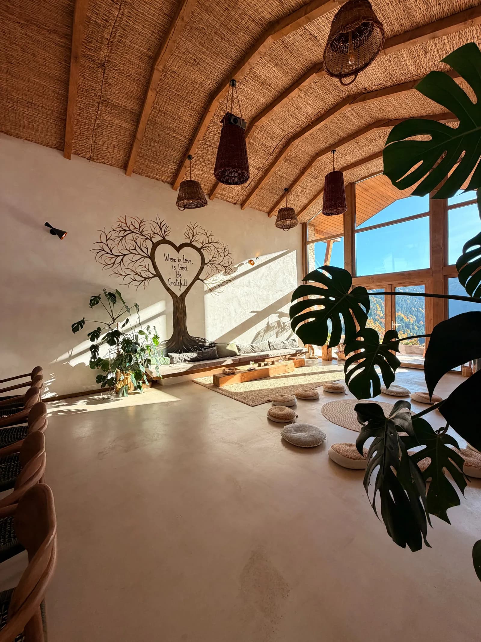Sala de yoga de la Mandala Retreat, cu copacul pictat pe perete și ferestre spre munte